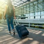 Reiziger met rolkoffer arriveert bij luchthaven
